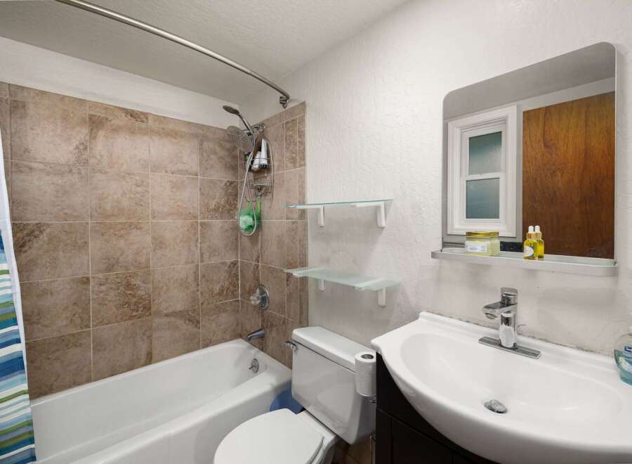 This bathroom features a tiled shower-tub combination with a modern showerhead and a convenient soap dish.
