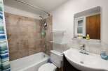 This bathroom features a tiled shower-tub combination with a modern showerhead and a convenient soap dish.