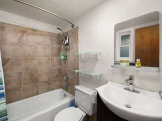 This bathroom features a tiled shower-tub combination with a modern showerhead and a convenient soap dish.