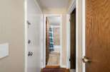 Step into this charming hallway, offering access to a bright bathroom with a blue and green striped shower curtain and tiled walls.