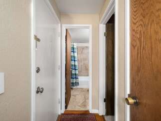 Step into this charming hallway, offering access to a bright bathroom with a blue and green striped shower curtain and tiled walls.