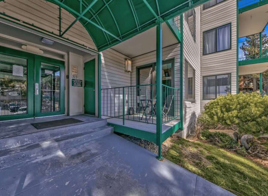 Discover comfortable living in this inviting property featuring a welcoming entrance with double green doors and a covered walkway.