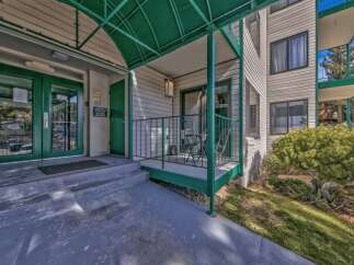 Discover comfortable living in this inviting property featuring a welcoming entrance with double green doors and a covered walkway.