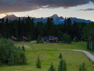 Experience serene mountain living in this picturesque property featuring multiple charming log cabins nestled amidst lush greenery.