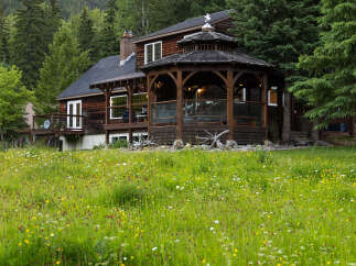 Experience rustic charm in this wooden cabin nestled amidst lush greenery and a vibrant wildflower meadow.