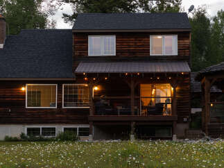 Experience rustic charm in this beautiful wooden home, featuring a covered porch with string lights perfect for evening relaxation.