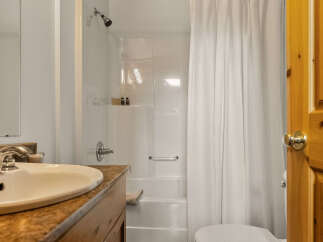 This bathroom features a clean and functional design with a white bathtub and shower combo, complemented by a white shower curtain.