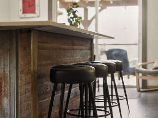 This modern kitchen features a rustic wooden island with a sleek countertop, complemented by three black bar stools.