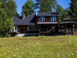 Nestled amidst lush greenery and a vibrant field of wildflowers, this charming wooden home offers a serene retreat.