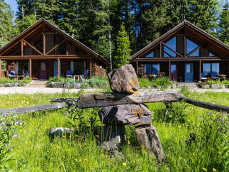 Experience rustic charm and natural beauty with these two log cabins nestled amongst tall evergreen trees.