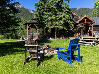 Enjoy the serene mountain setting from this charming property, featuring a cozy fire pit area with Adirondack chairs perfect for evening relaxation.