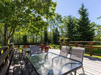 Enjoy outdoor dining and relaxation on this spacious wooden deck, complete with multiple tables and chairs perfect for gatherings.