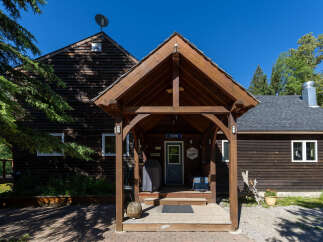 Charming wooden cabin with a welcoming covered porch, perfect for enjoying the serene natural surroundings.