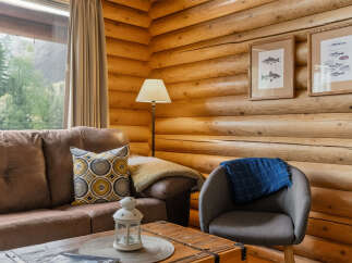 Experience rustic charm in this cozy living space featuring a plush brown sofa adorned with a decorative pillow and a warm throw.