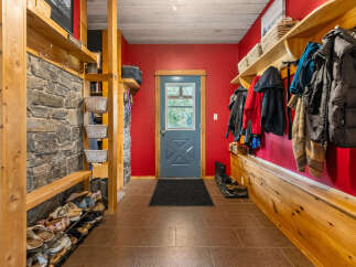 This charming entryway features a rustic stone accent wall and ample wooden shelving for storage.