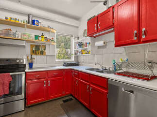 Brighten your culinary adventures in this vibrant kitchen, featuring striking red cabinetry that adds a pop of color to the space.