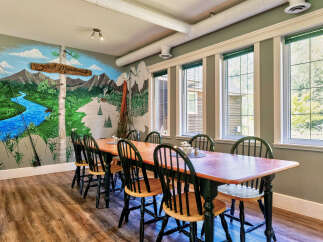 Experience the charm of this dining area, featuring a large wooden table surrounded by classic chairs, perfect for gatherings.