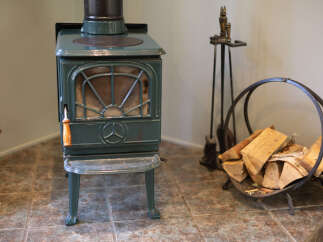 Cozy up by the charming green wood-burning stove, perfect for creating a warm and inviting atmosphere in your home.
