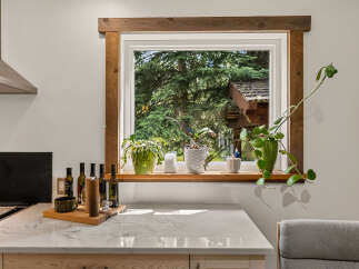 Enjoy cooking in this beautifully appointed kitchen, featuring a stunning marble countertop and a rustic wooden window frame that brings the outdoors in.