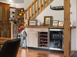 This rustic dining area features a charming wine display with a unique tree trunk holder and a built-in wine cabinet.