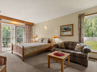 Experience comfort and tranquility in this charming bedroom featuring a cozy bed, a plush sofa, and a coffee table perfect for relaxation.