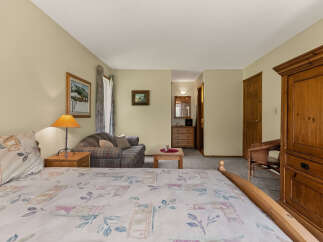 This charming bedroom offers a cozy retreat with a comfortable bed and a plaid sofa, perfect for relaxing.