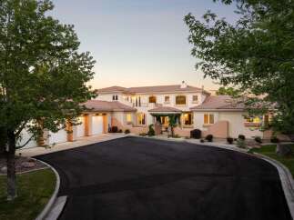 Discover this stunning Mediterranean-style estate, boasting a grand entrance with a covered portico and lush landscaping.