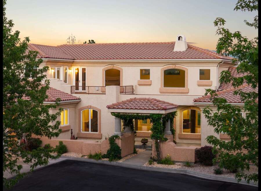 This stunning Mediterranean-style home features a beautiful terracotta tile roof and a charming vine-covered entryway.