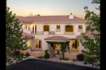 This stunning Mediterranean-style home features a beautiful terracotta tile roof and a charming vine-covered entryway.