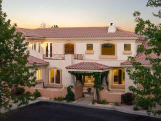This stunning Mediterranean-style home features a beautiful terracotta tile roof and a charming vine-covered entryway.