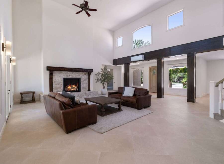 Experience luxury living in this grand living room featuring a soaring ceiling and a magnificent stone fireplace.