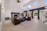 Experience luxury living in this grand living room featuring a soaring ceiling and a magnificent stone fireplace.