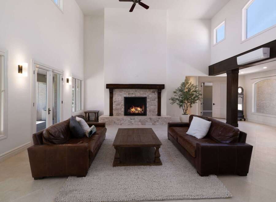 Experience luxurious living in this grand living room, featuring a soaring ceiling and a magnificent stone fireplace as the centerpiece.