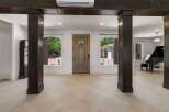 Step into a grand foyer featuring a beautiful wooden front door flanked by arched windows offering picturesque views of the lush outdoors.