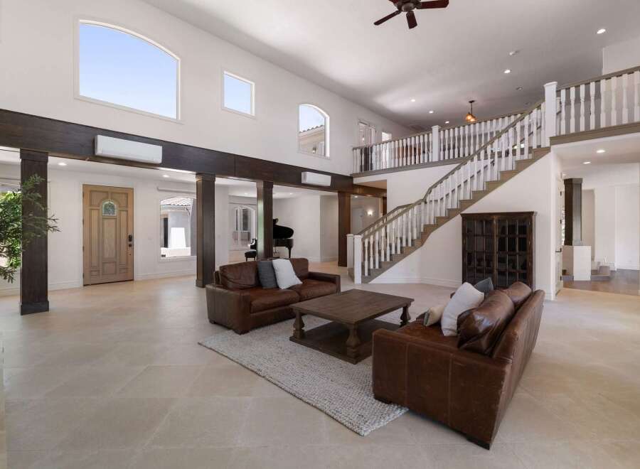 Experience luxury living in this grand foyer featuring a sweeping staircase and a dramatic two-story ceiling.