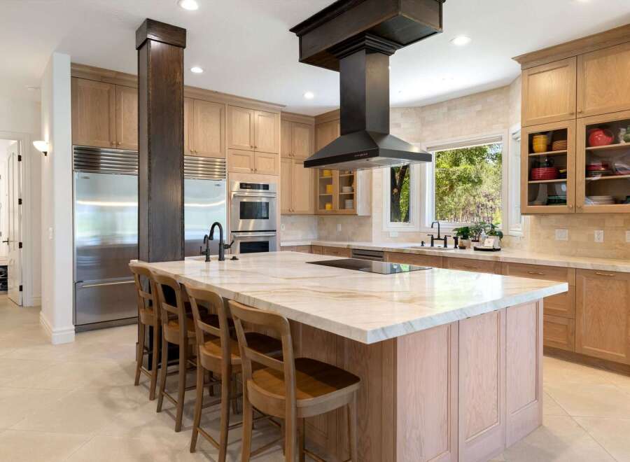 Experience luxury in this stunning gourmet kitchen, featuring a large marble island with a built-in cooktop and seating.
