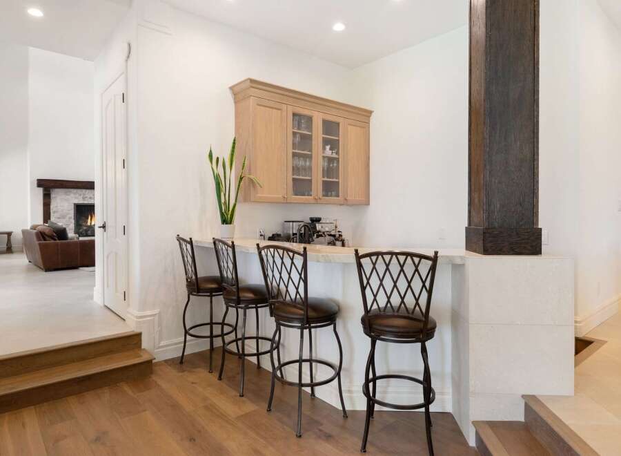 This elegant home features a sophisticated bar area perfect for entertaining, complete with a built-in cabinet and comfortable bar stools.