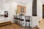 This elegant home features a sophisticated bar area perfect for entertaining, complete with a built-in cabinet and comfortable bar stools.
