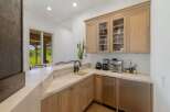 This stunning wet bar features a sleek marble countertop and backsplash, complemented by custom light wood cabinetry.