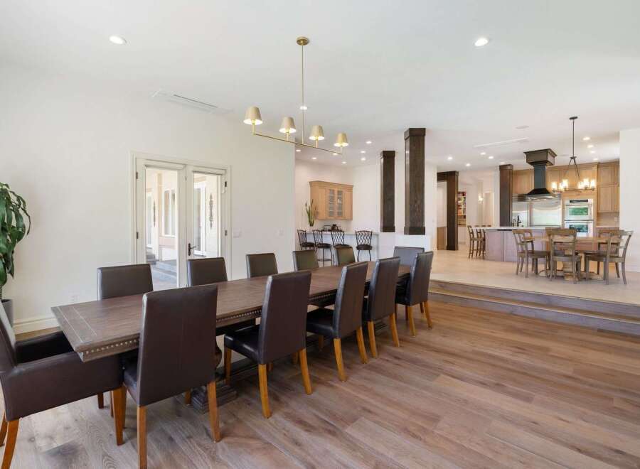 Experience elegant dining in this spacious home, featuring a large wooden dining table with plush leather chairs perfect for hosting.