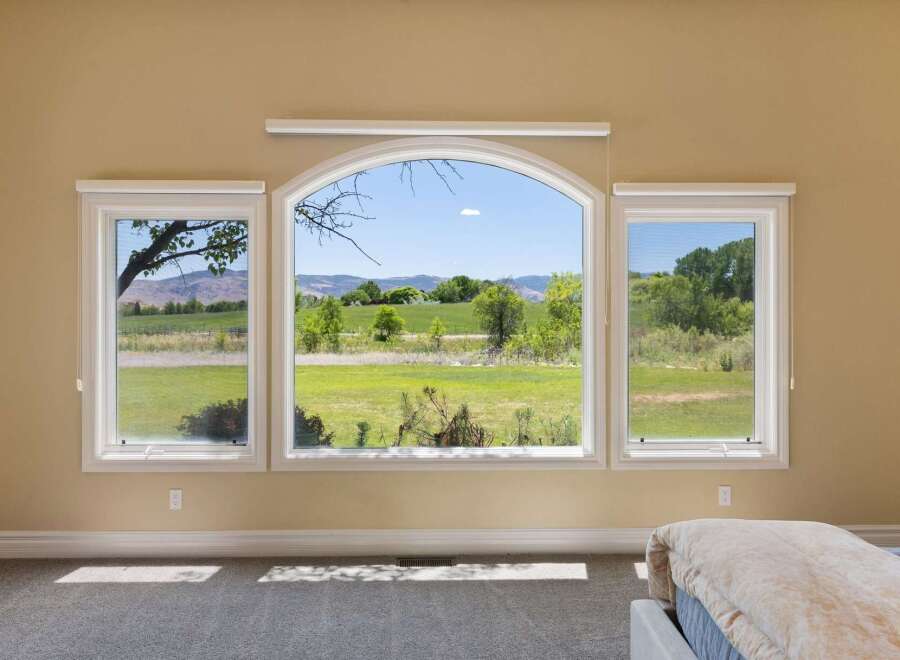 Experience breathtaking panoramic views from this stunning property, featuring a large arched window complemented by two side windows.