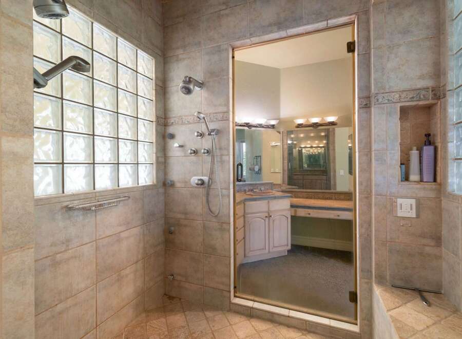 Experience luxury in this spacious bathroom featuring a walk-in shower with multiple shower heads and a large glass enclosure.