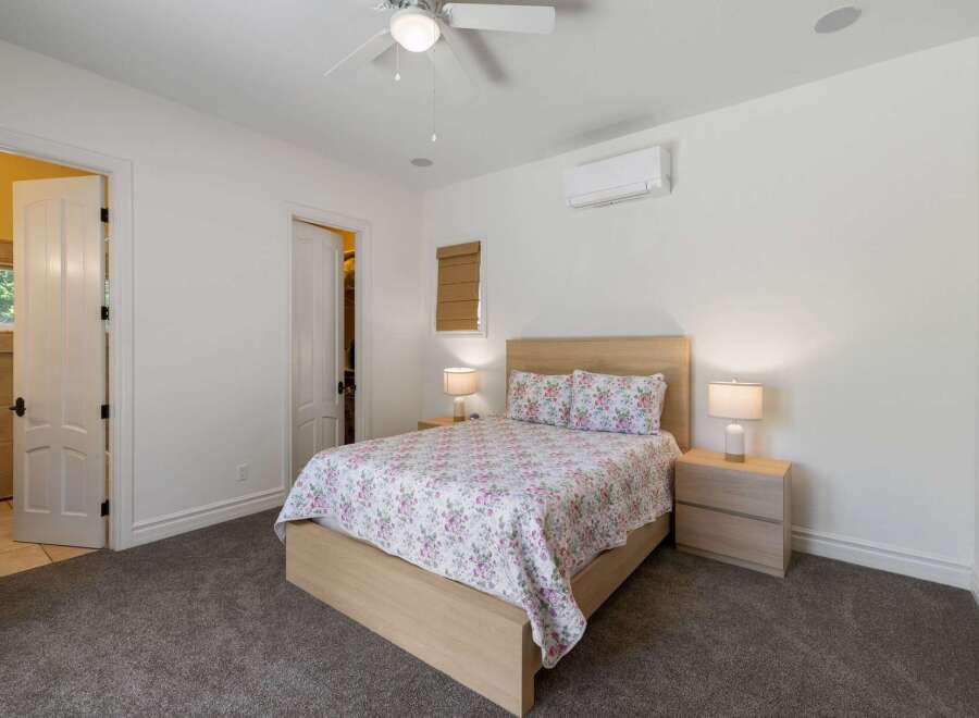 This inviting bedroom features a comfortable queen-size bed with a floral comforter and matching pillows, complemented by two wooden nightstands with lamps.