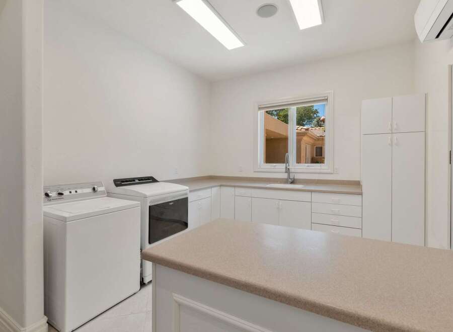 This spacious laundry room features a large island countertop, perfect for folding clothes or additional workspace.