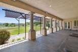 Enjoy the outdoors from this covered patio featuring elegant columns and a pergola, perfect for al fresco dining or relaxing with a view.