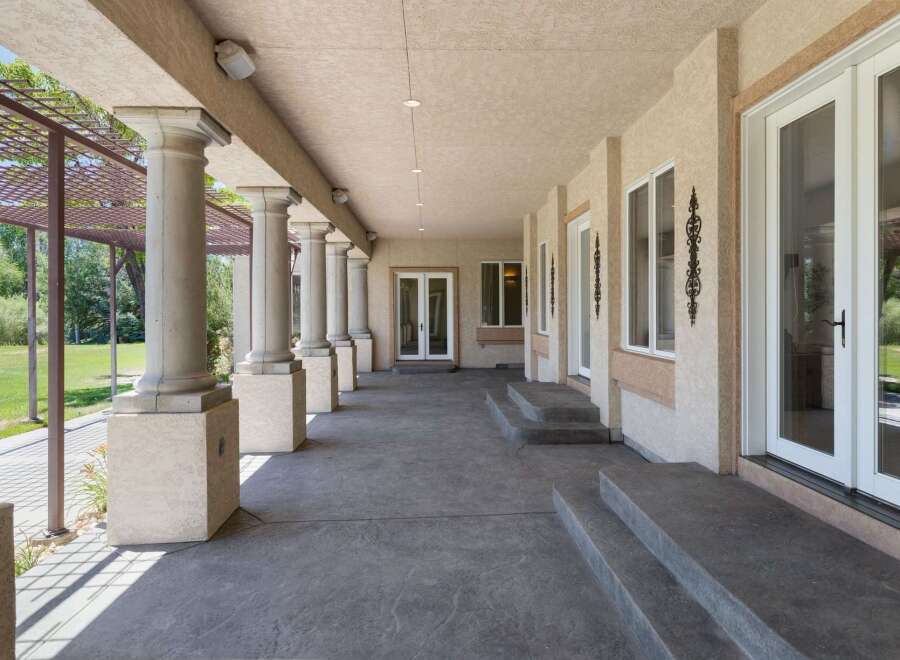 Experience elegant outdoor living with this expansive covered patio, featuring grand columns and a textured concrete floor.