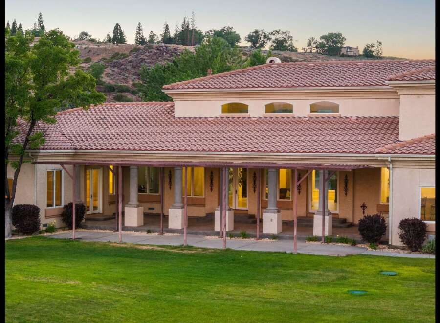This stunning home features a beautiful tiled roof and a covered porch supported by elegant columns, perfect for enjoying the outdoors.