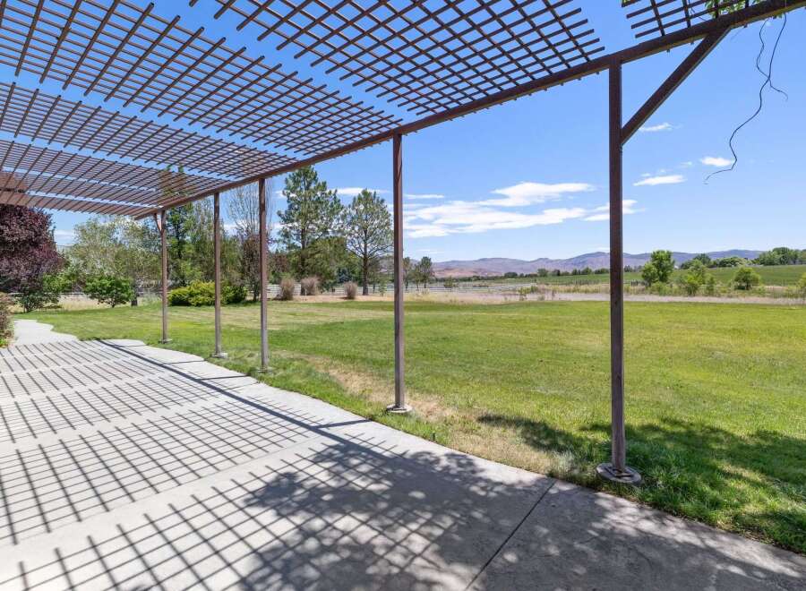 Enjoy the stunning panoramic views from this property's expansive patio, complete with a charming pergola offering dappled shade.