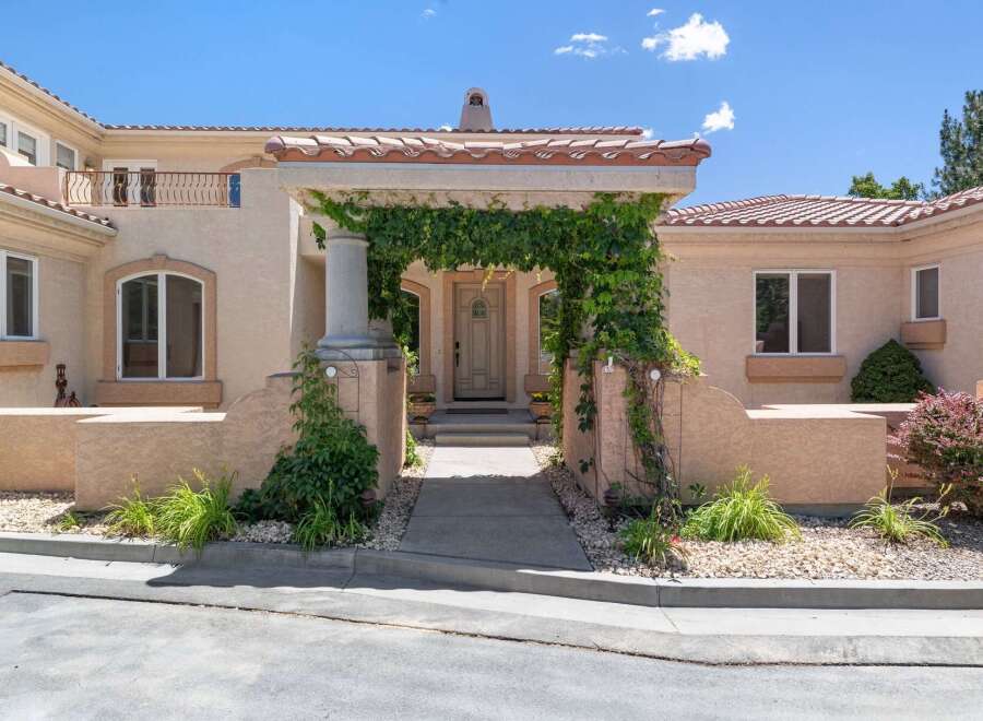 Welcome to this stunning Mediterranean-style home, featuring a grand entrance with a vine-covered archway leading to a beautifully crafted double door.