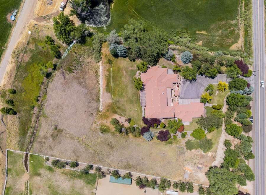 Discover this expansive property featuring a large, multi-winged home with a terracotta tile roof, surrounded by lush greenery and mature trees.